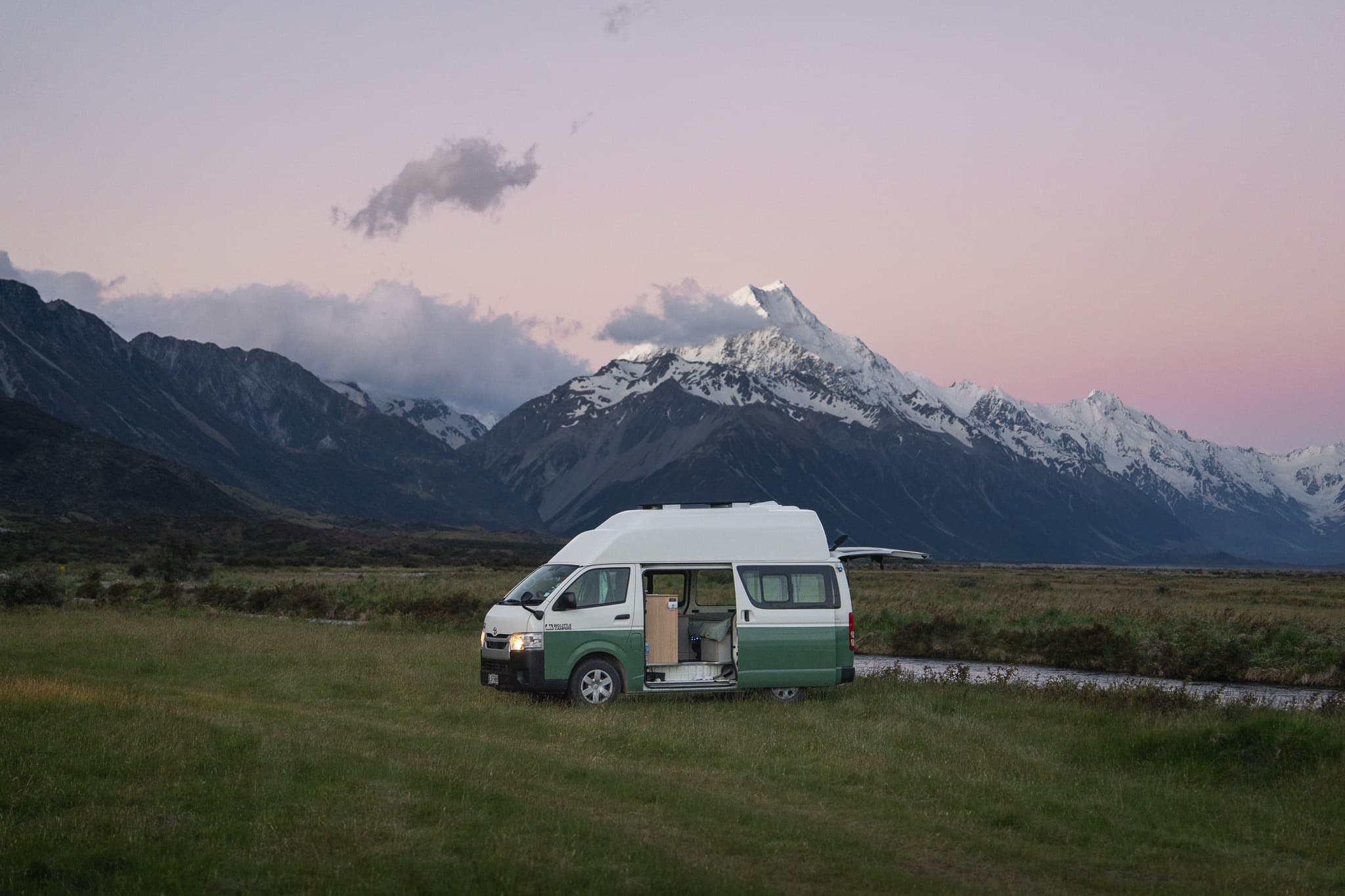 Campervan at dusk with snow-capped peaks in New Zealand